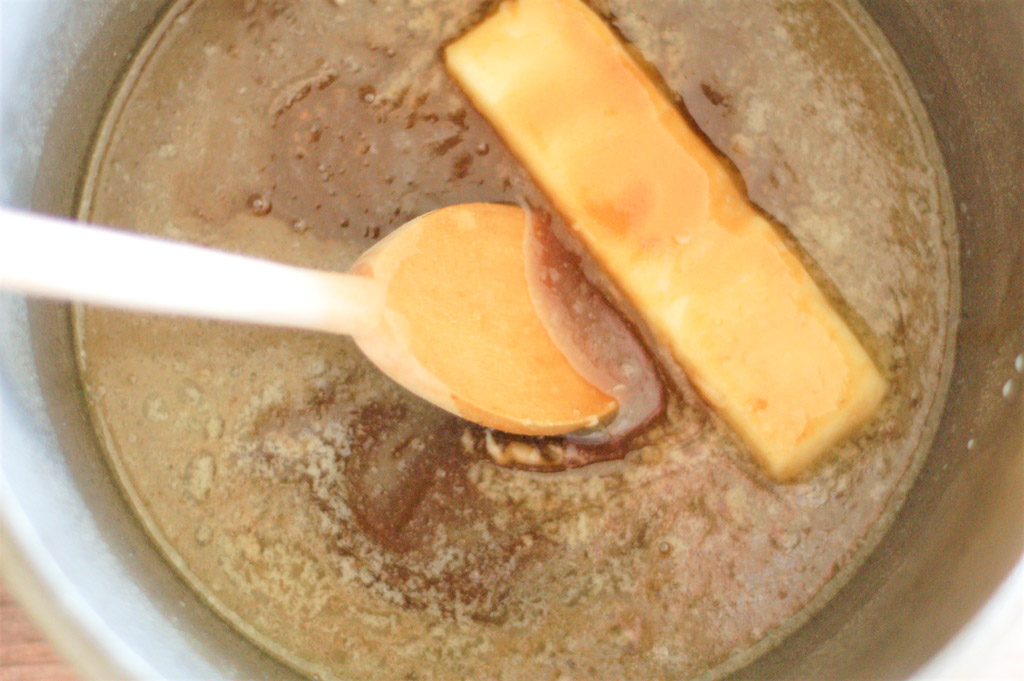 sauce pan with a melting stick of butter in gooey caramel sauce