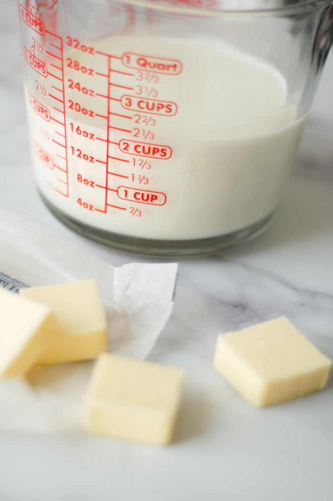 liquid measuring dish filled with milk next to pieces of butter