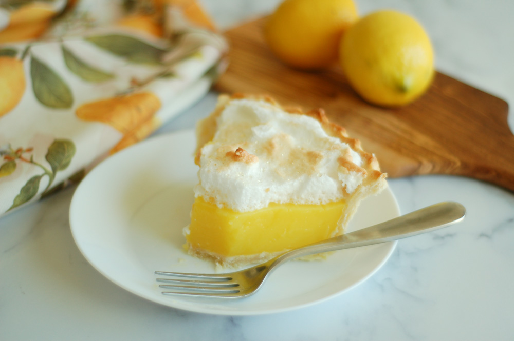slice of lemon meringue pie on a white plate with a fork