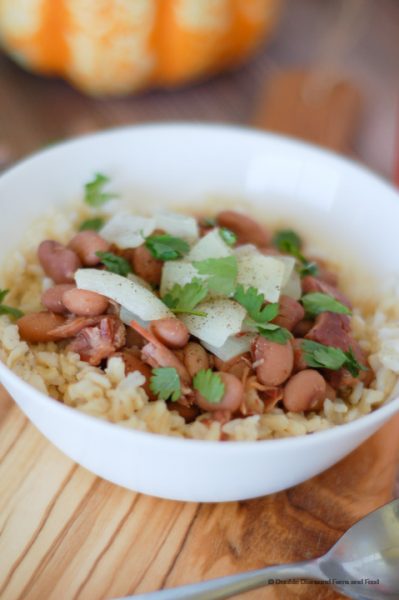 A bowl with rice, beans, and ham garnished with onions and chopped cilantro